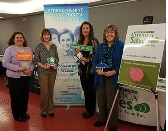 Members of the Connecticut Saves team pose with proclamation for Connecticut Saves week in front of the savings banner