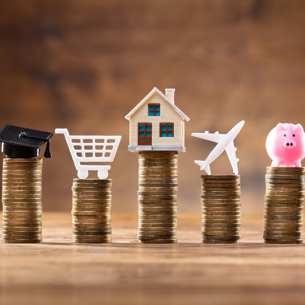 stack of coins with graduation cap, shopping cart, house, airplane, and piggy bank figures on top